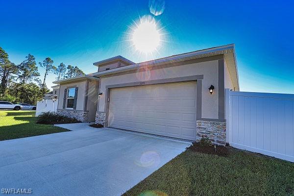 3393 Kacher Rd, North Port, FL 34288 - view of front of house featuring stone siding, concrete driveway, stucco siding, and an attached garage