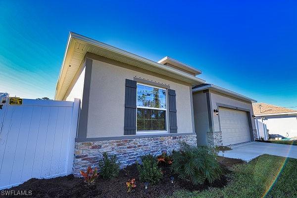 3393 Kacher Rd, North Port, FL 34288 - view of home's exterior with stucco siding, stone siding, a garage, and driveway