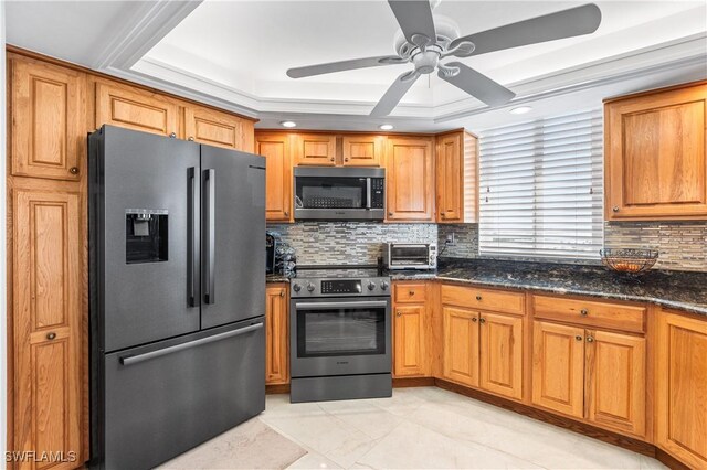 4745 Estero Blvd Unit 1002, Fort Myers Beach, FL 33931 - kitchen with appliances with stainless steel finishes, a ceiling fan, tasteful backsplash, dark stone counters, and brown cabinetry