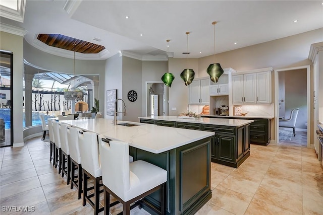 12850 Terabella Way, Fort Myers, FL 33912 - kitchen featuring a large island with sink, a kitchen breakfast bar, light tile patterned floors, tasteful backsplash, and crown molding