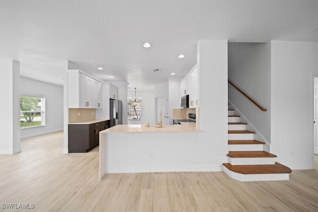 11544 Lake Cypress Loop, Fort Myers, FL 33913 - kitchen featuring light wood-style floors, appliances with stainless steel finishes, light countertops, a chandelier, and white cabinetry
