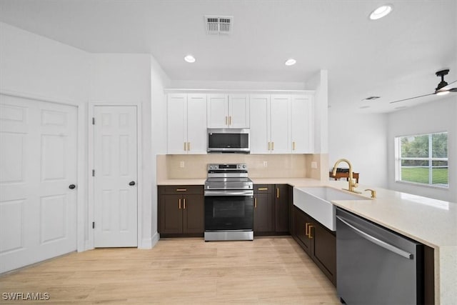11544 Lake Cypress Loop, Fort Myers, FL 33913 - kitchen with stainless steel appliances, light countertops, white cabinets, a peninsula, and tasteful backsplash