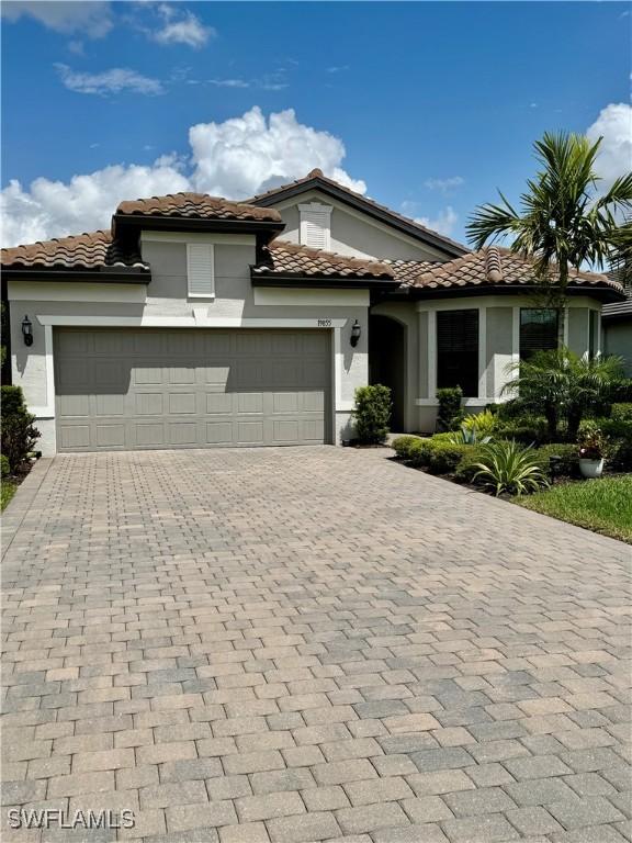 19855 Beverly Park Rd, Estero, FL 33928 - mediterranean / spanish-style home featuring decorative driveway, stucco siding, an attached garage, and a tile roof