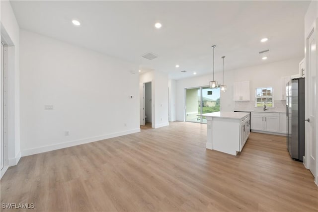 3111 11th St W, Lehigh Acres, FL 33971 - kitchen featuring stainless steel fridge with ice dispenser, a kitchen island, white cabinets, recessed lighting, and open floor plan