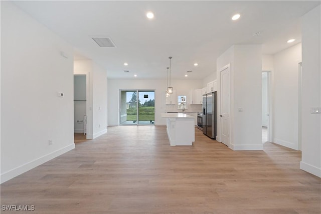 3111 11th St W, Lehigh Acres, FL 33971 - kitchen featuring stainless steel fridge, open floor plan, white cabinets, light countertops, and recessed lighting
