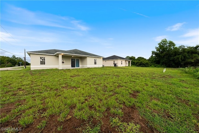 3111 11th St W, Lehigh Acres, FL 33971 - back of house featuring stucco siding and a yard