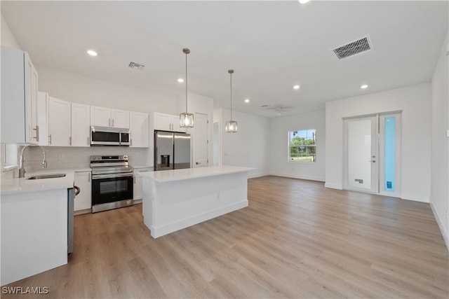 3111 11th St W, Lehigh Acres, FL 33971 - kitchen with stainless steel appliances, a kitchen island, light wood finished floors, light countertops, and recessed lighting