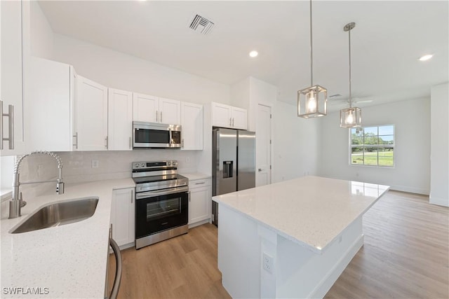 3111 11th St W, Lehigh Acres, FL 33971 - kitchen with appliances with stainless steel finishes, light wood-style flooring, a kitchen island, white cabinetry, and light stone countertops