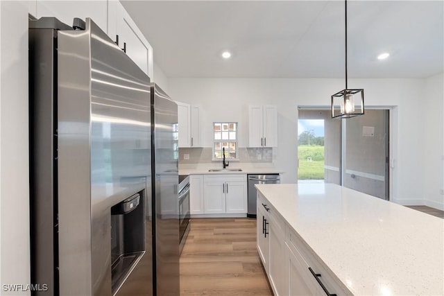 3109 11th St W, Lehigh Acres, FL 33971 - kitchen featuring stainless steel appliances, light wood-style floors, white cabinets, recessed lighting, and hanging light fixtures