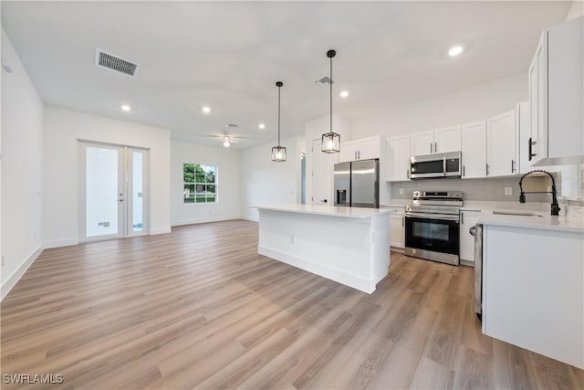 3109 11th St W, Lehigh Acres, FL 33971 - kitchen with appliances with stainless steel finishes, light countertops, a center island, light wood finished floors, and open floor plan