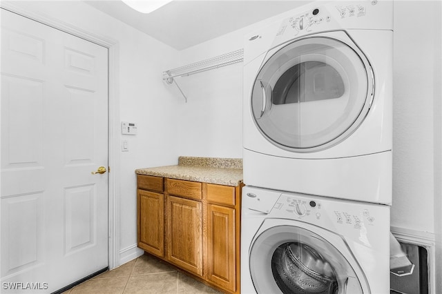 14813 Canton Ct, Naples, FL 34114 - washroom featuring estacked washer and dryer, cabinet space, and light tile patterned floors