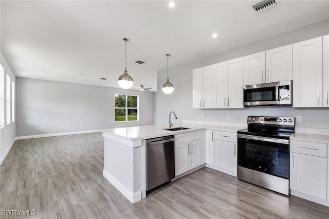 1909 Moore Ave, Lehigh Acres, FL 33972 - kitchen with stainless steel appliances, light wood-style flooring, a peninsula, white cabinetry, and open floor plan
