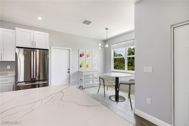 1909 Moore Ave, Lehigh Acres, FL 33972 - bedroom featuring freestanding refrigerator, dark wood-style flooring, a chandelier, and a textured ceiling
