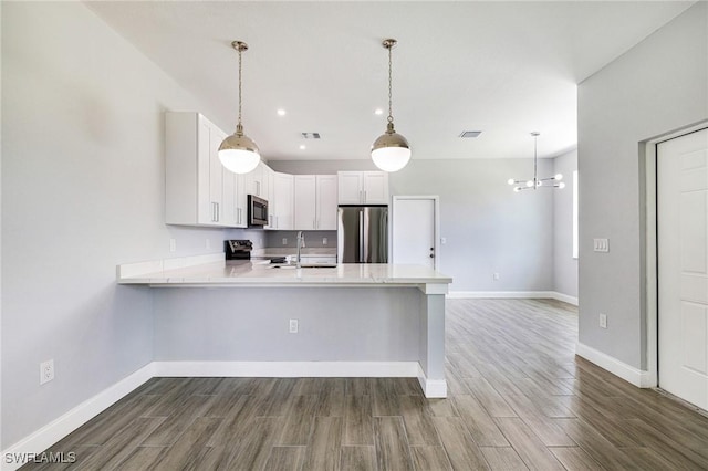 1909 Moore Ave, Lehigh Acres, FL 33972 - kitchen featuring stainless steel appliances, a peninsula, light countertops, dark wood-style flooring, and recessed lighting