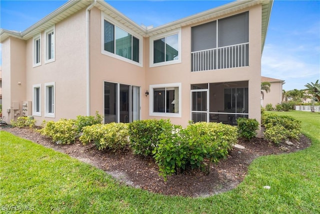 76 4th St Unit 2-102, Bonita Springs, FL 34134 - rear view of property featuring stucco siding and a lawn
