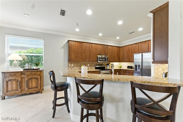 6899 Del Mar Ter, Naples, FL 34105 - kitchen featuring stainless steel appliances, light stone counters, a peninsula, backsplash, and crown molding