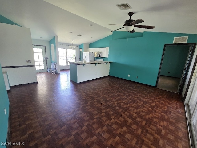 3022 34th St SW, Lehigh Acres, FL 33976 - unfurnished living room featuring vaulted ceiling, a chandelier, and a ceiling fan