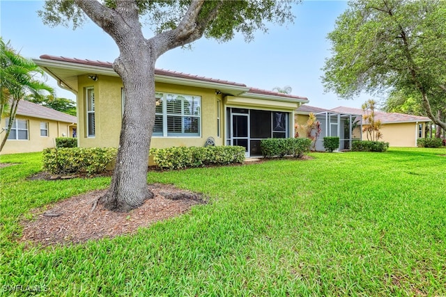 4776 Fairloop Run, Lehigh Acres, FL 33973 - rear view of house featuring a yard, stucco siding, a sunroom, and a tiled roof