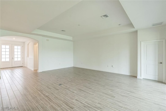 1801 Hagen Ct, Naples, FL 34120 - spare room featuring arched walkways, a raised ceiling, french doors, and light wood-style flooring
