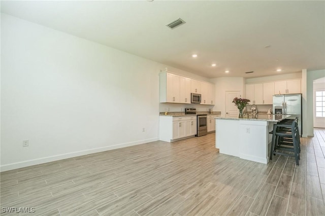 1801 Hagen Ct, Naples, FL 34120 - kitchen featuring appliances with stainless steel finishes, light wood finished floors, a kitchen breakfast bar, white cabinets, and recessed lighting