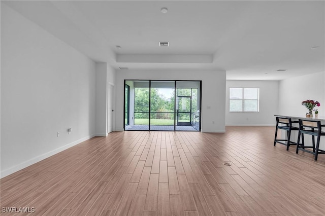 1801 Hagen Ct, Naples, FL 34120 - unfurnished living room featuring a tray ceiling and light wood finished floors
