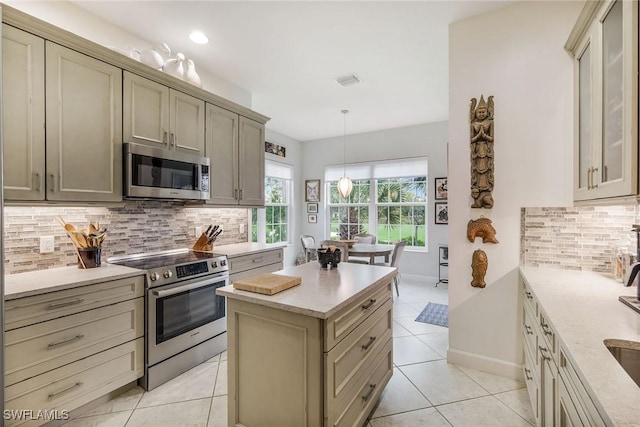 23751 Merano Ct Unit 201, Estero, FL 34134 - kitchen featuring stainless steel appliances, light tile patterned floors, backsplash, hanging light fixtures, and glass insert cabinets