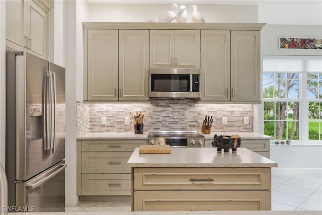 23751 Merano Ct Unit 201, Estero, FL 34134 - kitchen with stainless steel appliances, cream cabinetry, backsplash, light tile patterned floors, and light countertops