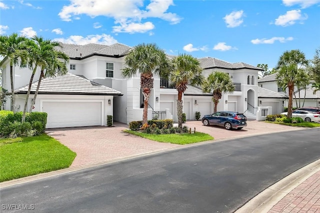 23751 Merano Ct Unit 201, Estero, FL 34134 - view of front of house with stucco siding, a tile roof, decorative driveway, a residential view, and an attached garage