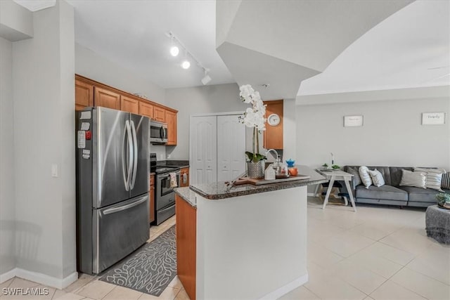 13010 Positano Cir Unit 206, Naples, FL 34105 - kitchen with stainless steel appliances, light tile patterned floors, open floor plan, dark stone counters, and a peninsula