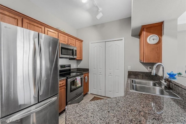13010 Positano Cir Unit 206, Naples, FL 34105 - kitchen with appliances with stainless steel finishes, light tile patterned floors, rail lighting, and brown cabinetry