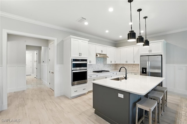 8951 Saint Lucia Dr, Naples, FL 34114 - kitchen featuring stainless steel appliances, white cabinets, a breakfast bar area, an island with sink, and under cabinet range hood