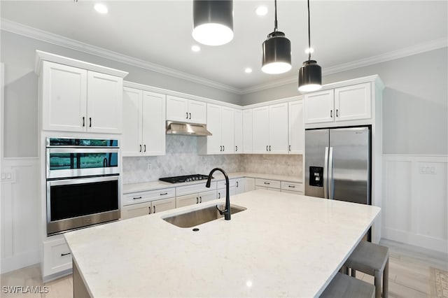 8951 Saint Lucia Dr, Naples, FL 34114 - kitchen with appliances with stainless steel finishes, a kitchen bar, white cabinetry, a center island with sink, and crown molding