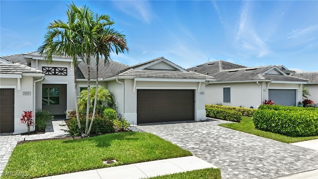8951 Saint Lucia Dr, Naples, FL 34114 - view of front of house with an attached garage, stucco siding, decorative driveway, and a front yard
