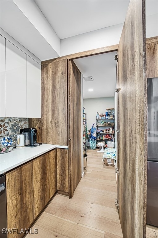 675 Logan Blvd S, Naples, FL 34119 - kitchen featuring light wood finished floors, white cabinets, decorative backsplash, light countertops, and stainless steel appliances