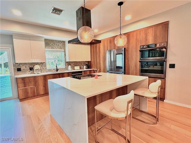 675 Logan Blvd S, Naples, FL 34119 - kitchen with black appliances, light wood-type flooring, brown cabinetry, modern cabinets, and recessed lighting