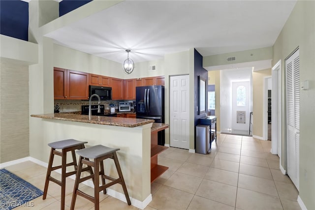 20310 Estero Gardens Cir Unit 203, Estero, FL 33928 - kitchen with black appliances, a peninsula, light tile patterned floors, and decorative backsplash