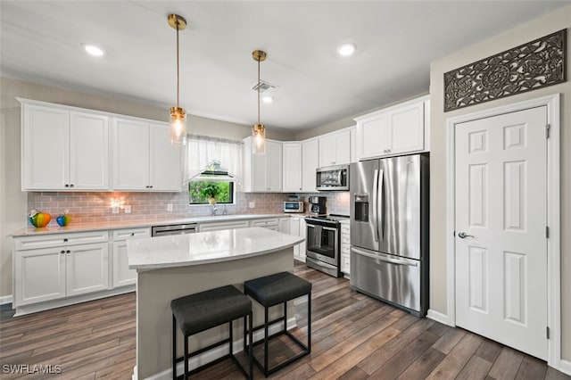 19280 Elston Way, Estero, FL 33928 - kitchen featuring stainless steel appliances, dark wood-style flooring, decorative backsplash, white cabinetry, and a kitchen island
