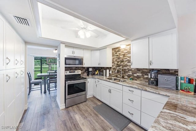 402 Bristle Cone Ln Unit 2, Naples, FL 34113 - kitchen with stainless steel appliances, a tray ceiling, ceiling fan, decorative backsplash, and white cabinetry