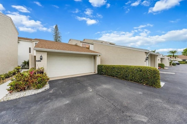 402 Bristle Cone Ln Unit 2, Naples, FL 34113 - view of side of home featuring driveway, an attached garage, and stucco siding
