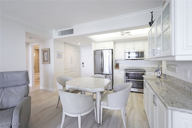 180 Seaview Ct Unit 215, Marco Island, FL 34145 - kitchen featuring appliances with stainless steel finishes, light wood-style floors, white cabinets, crown molding, and light stone countertops