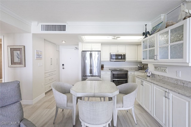 180 Seaview Ct Unit 215, Marco Island, FL 34145 - kitchen with stainless steel appliances, light wood-style flooring, ornamental molding, glass insert cabinets, and light stone counters