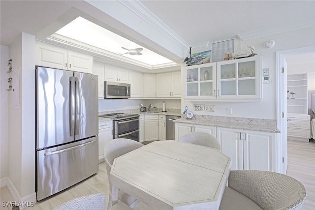 180 Seaview Ct Unit 215, Marco Island, FL 34145 - kitchen featuring appliances with stainless steel finishes, ornamental molding, glass insert cabinets, white cabinetry, and light wood-type flooring