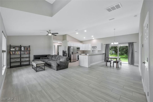 1417 Acacia Ave, Lehigh Acres, FL 33972 - living room featuring lofted ceiling, a ceiling fan, a chandelier, and light wood-style flooring