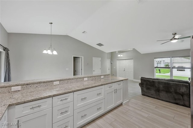 1417 Acacia Ave, Lehigh Acres, FL 33972 - kitchen featuring open floor plan, vaulted ceiling, a ceiling fan, white cabinetry, and a chandelier