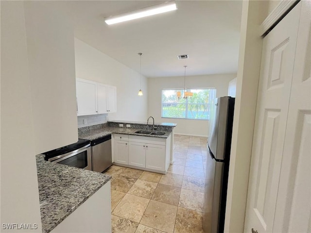 812 Grand Rapids Blvd, Naples, FL 34120 - kitchen featuring stainless steel appliances, a peninsula, white cabinetry, dark stone counters, and hanging light fixtures