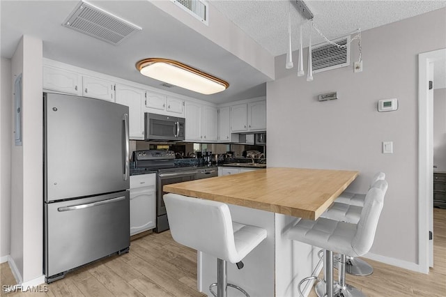 180 Seaview Ct Unit 612, Marco Island, FL 34145 - kitchen featuring stainless steel appliances, a kitchen bar, light wood-type flooring, white cabinetry, and a peninsula