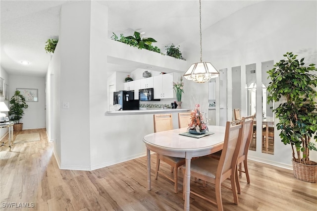 800 New Waterford Dr Unit A202, Naples, FL 34104 - dining area featuring a chandelier, light wood-type flooring, and a high ceiling