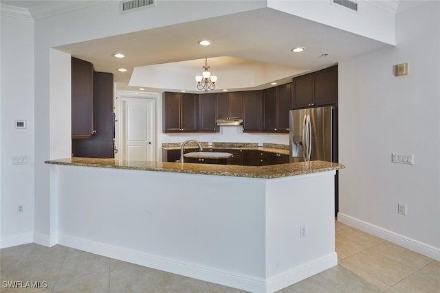 24011 Via Castella Dr Unit 2402, Bonita Springs, FL 34134 - kitchen with stainless steel refrigerator with ice dispenser, dark stone countertops, under cabinet range hood, dark brown cabinetry, and crown molding