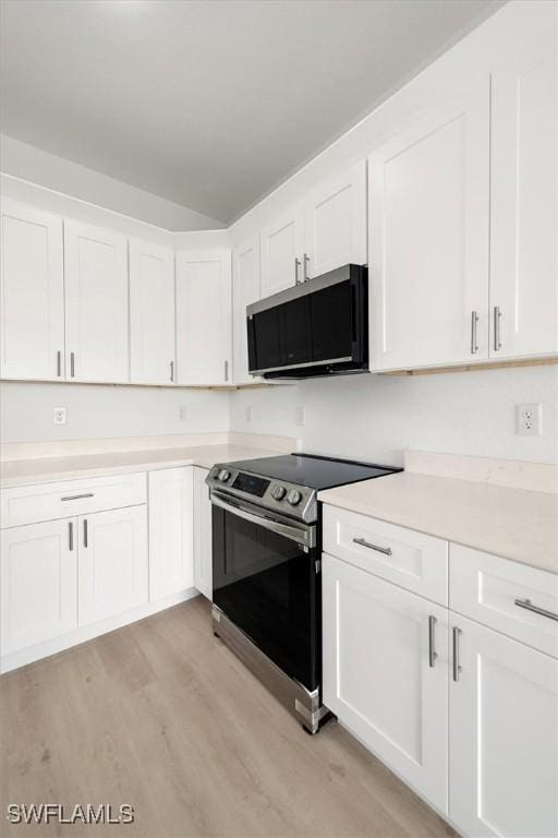 9013 Largo Cir, Labelle, FL 33935 - kitchen with electric range, light wood-style flooring, white cabinets, and light countertops