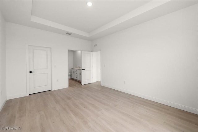 9013 Largo Cir, Labelle, FL 33935 - unfurnished bedroom with a raised ceiling, light wood-type flooring, recessed lighting, and ensuite bathroom